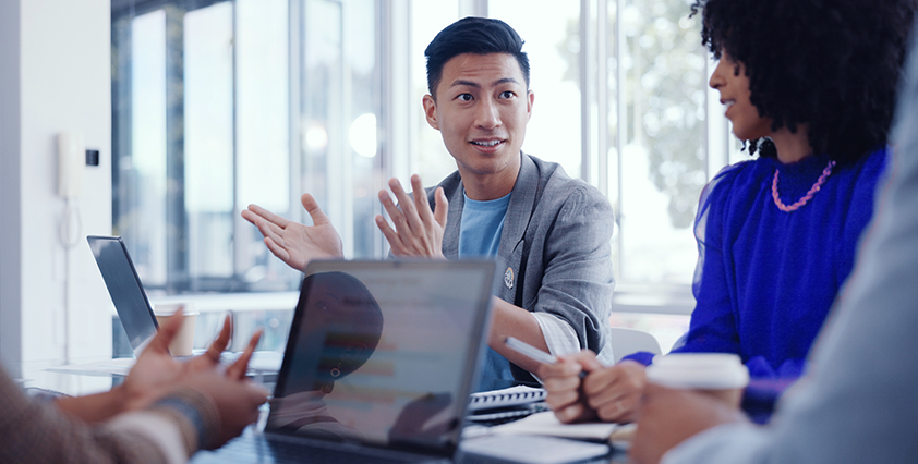 Homem asiático participando de reunião de negócios, discute ideias com colegas em ambiente de centro de serviços compartilhados.