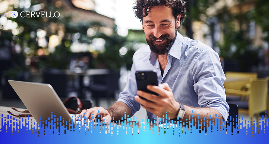 Homem sorridente usando smartphone e notebook ao ar livre, ilustrando a gestão de conhecimento nas empresas para melhorar a produtividade e inovação.