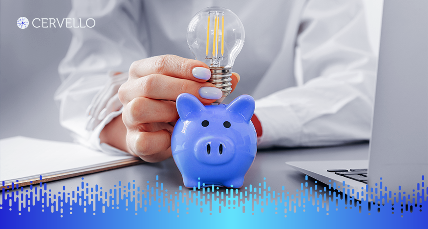 Imagem de uma mão segurando uma lâmpada e um cofrinho de porquinho azul, simbolizando economia e redução de custos operacionais em negócios.